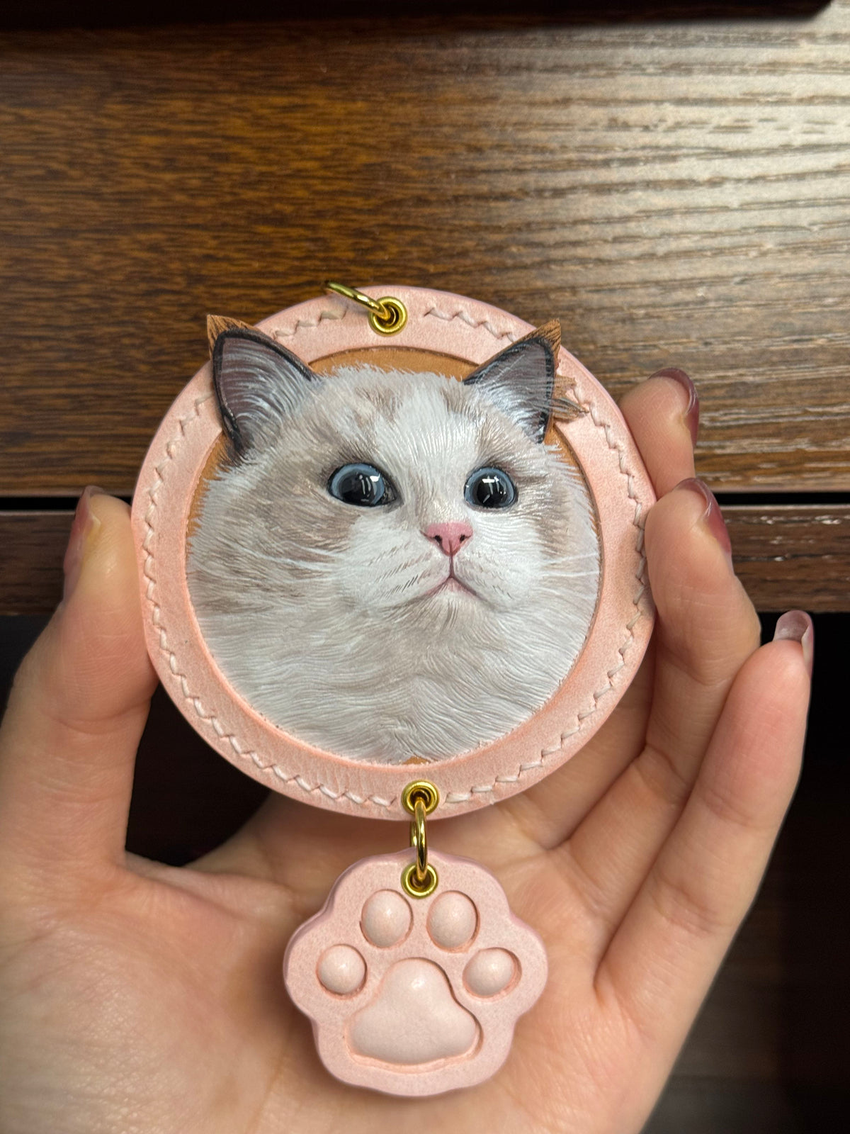 Cat face key ring ornament in pink stitched leather with hanging paw charm