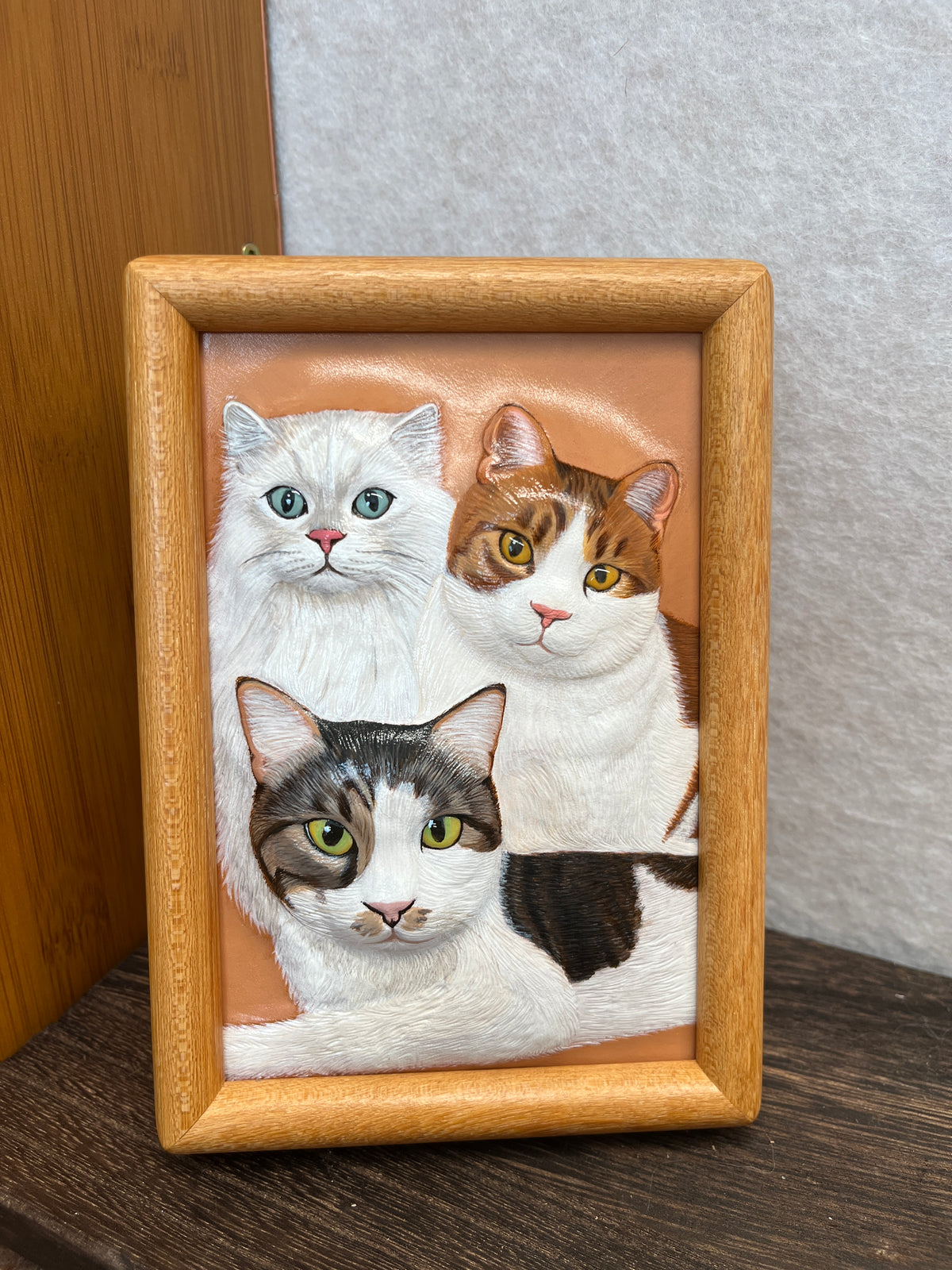 Custom handmade leather pet photo panel with stitched portrait border, showing three cat faces